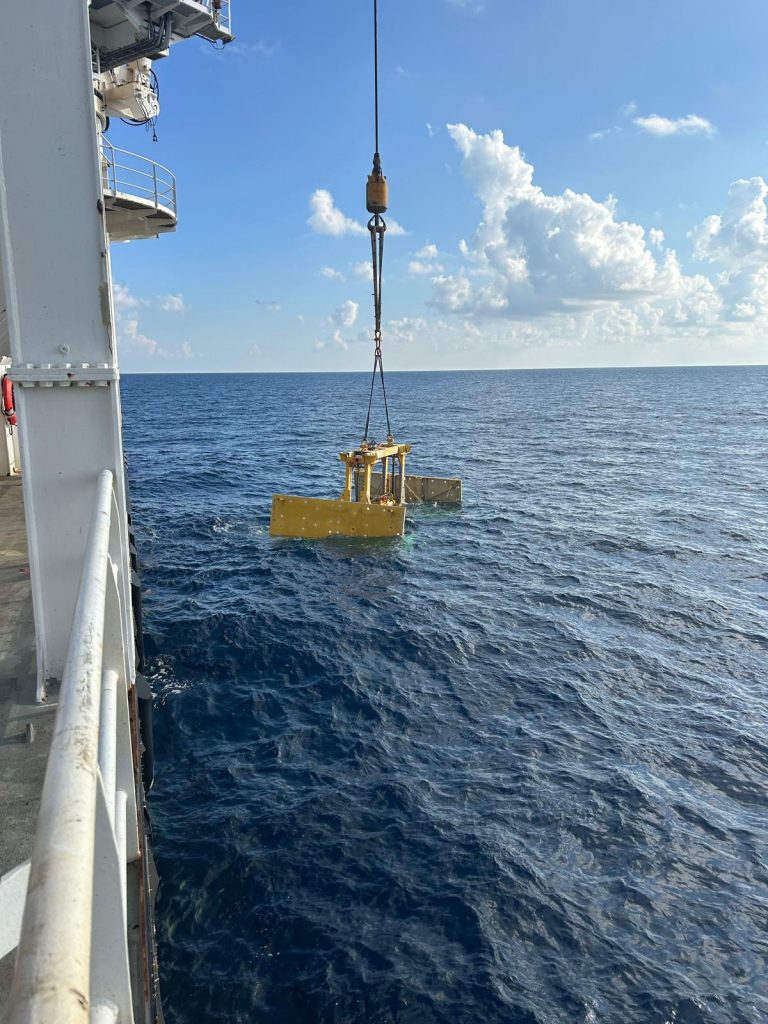 Pipe lift frame being deployed into waters offshore.