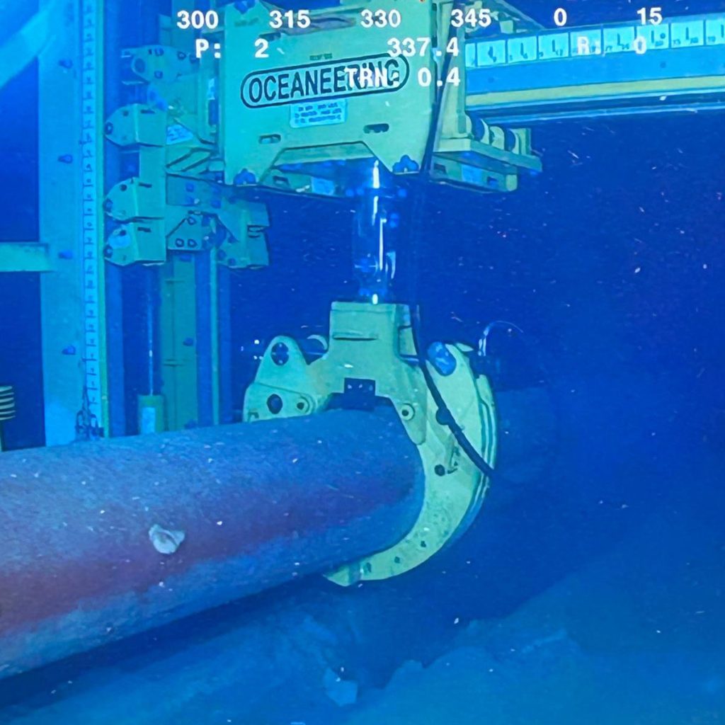 Pipe lift frame clamp holding subsea pipeline off sea floor.