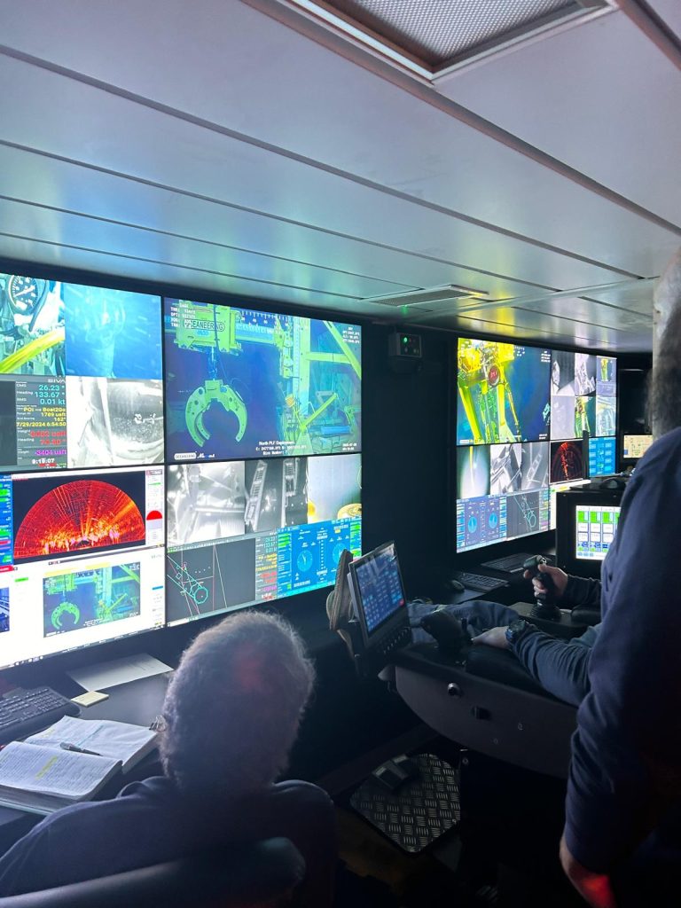 Offshore operations monitoring center watching pipe lift scope. Monitors with images.