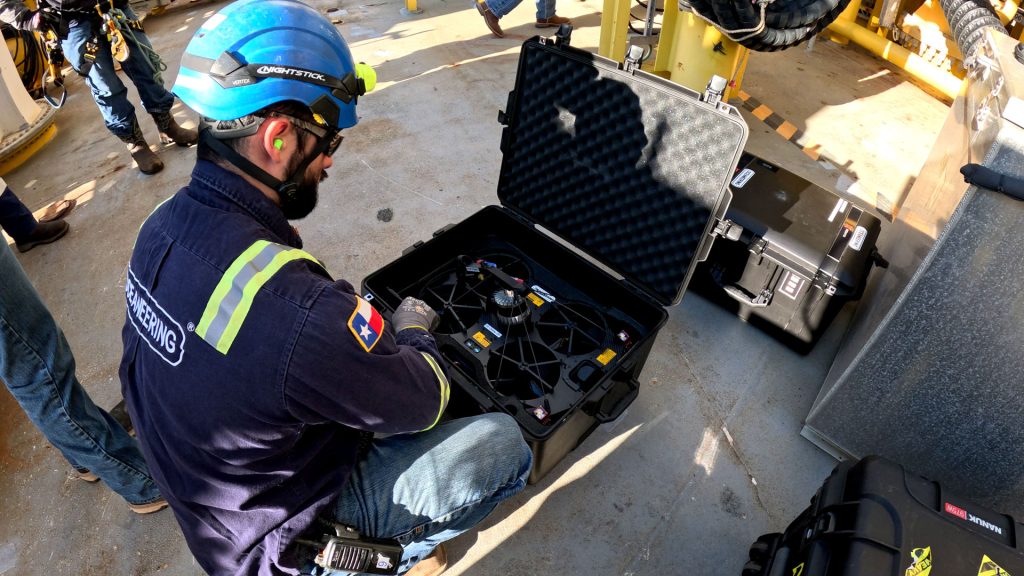 Technician looks at case holding drone used for internal tank inspections.