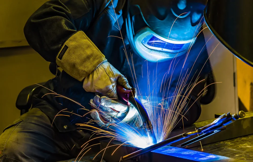 Welder works on a submarine part with bright sparks flying during welding
