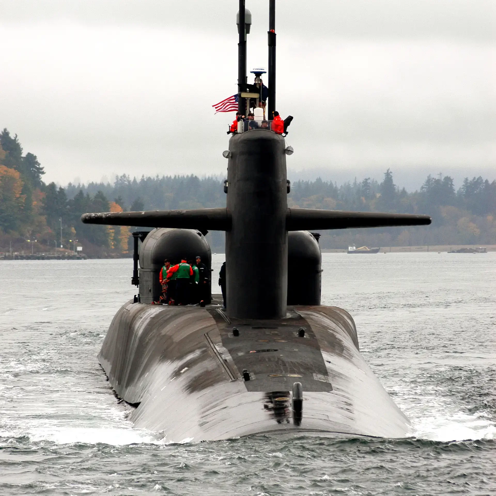 An Ohio class guided missile submarine partially submerged in the water with two dry deck shelters mounted on its deck
