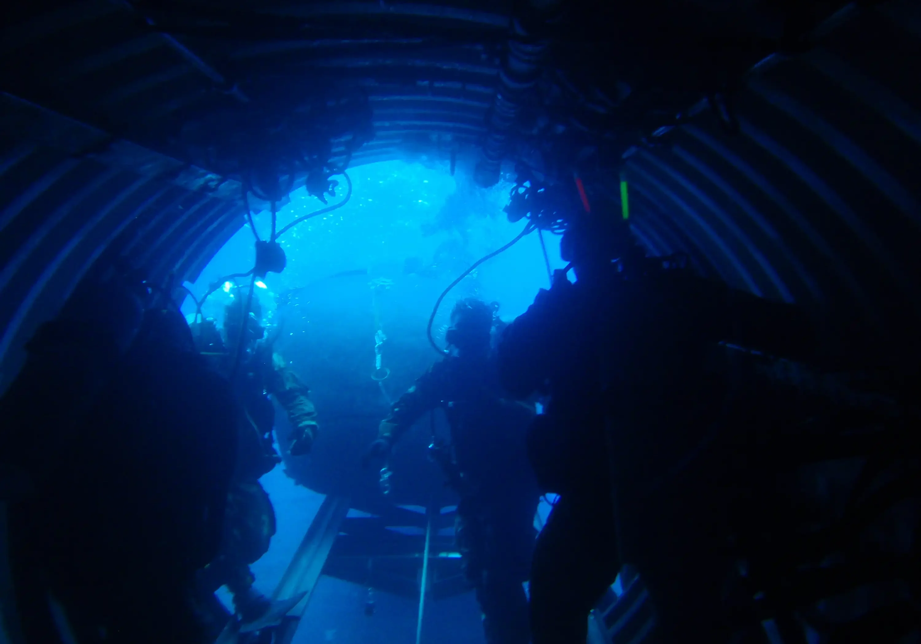 Divers underwater inside deep submergence system with hatch open